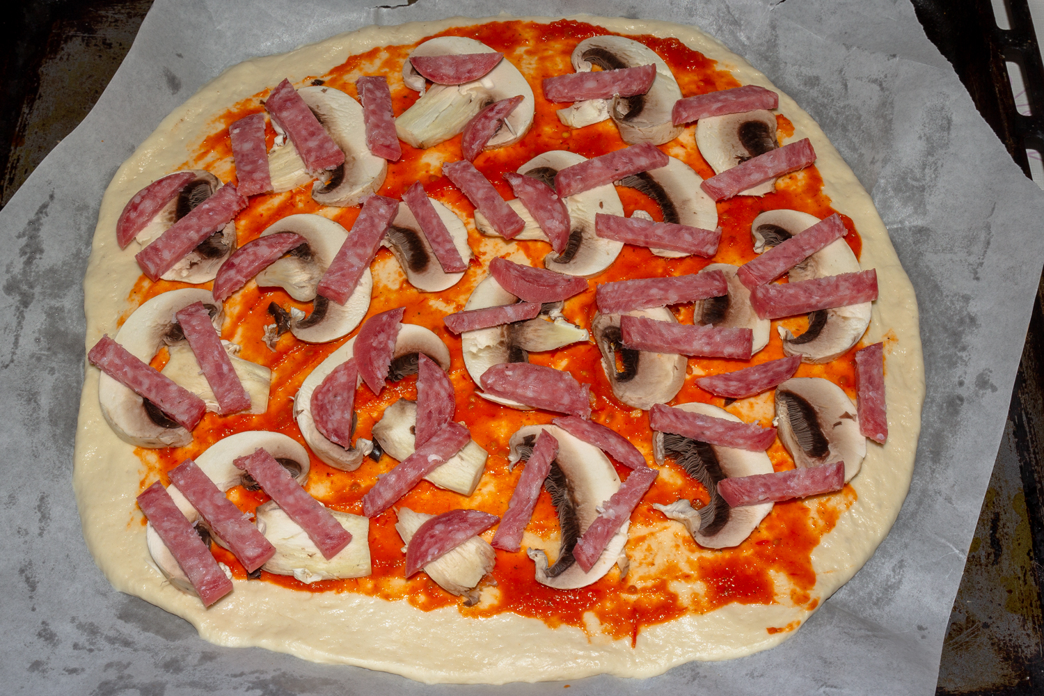 колбаса и грибы выложенные на тесто по рецепту Пицца с колбасой грибами и сыром